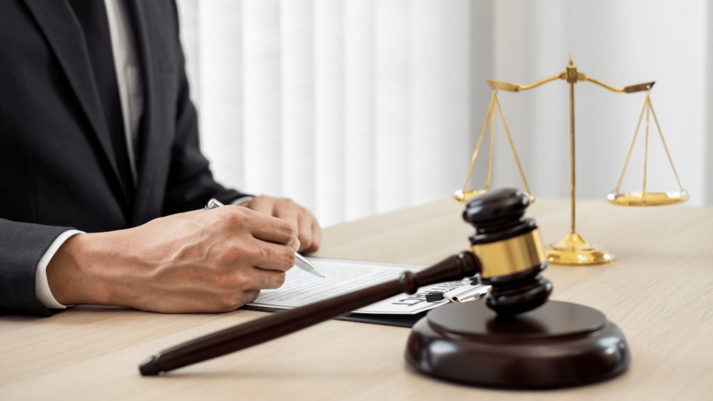 A lawyer writing on a notepad in front of a judge's gavel and scales of justice