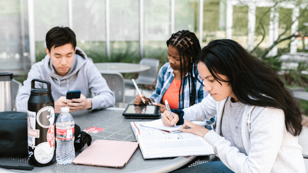 a group of students sitting at a table in an outdoor area