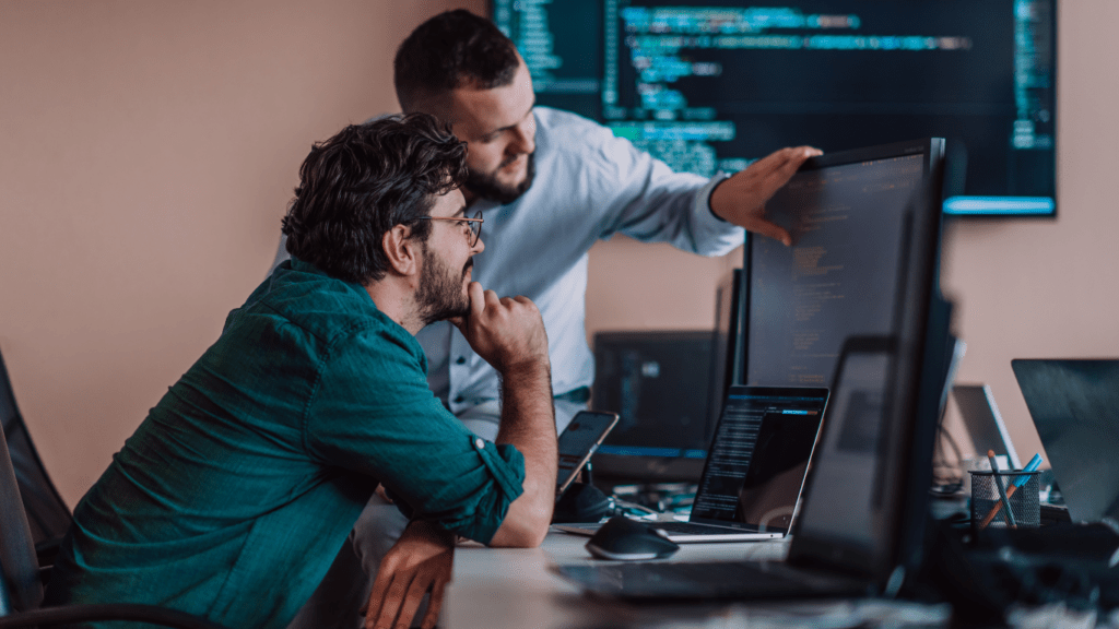 two people working on a computer in front of a monitor